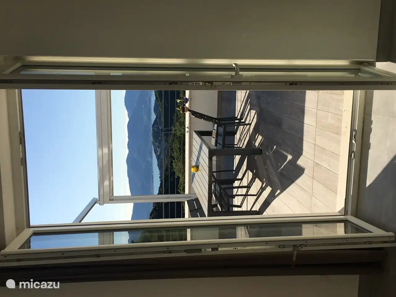 Vista al mar y terraza desde el interior del apartamento por la tarde.