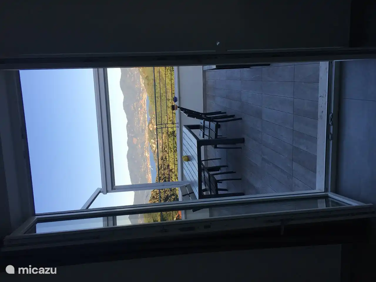 Vista al mar y terraza desde el interior del apartamento por la mañana.