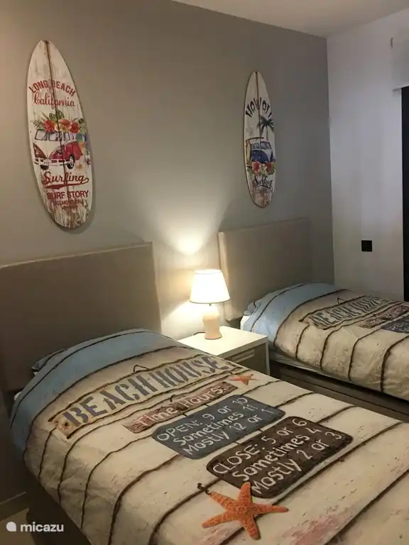 Bedroom II. This bedroom has two single beds with bedside table, a large built-in wardrobe with space for hanging and laying clothes, heating and air conditioning. 