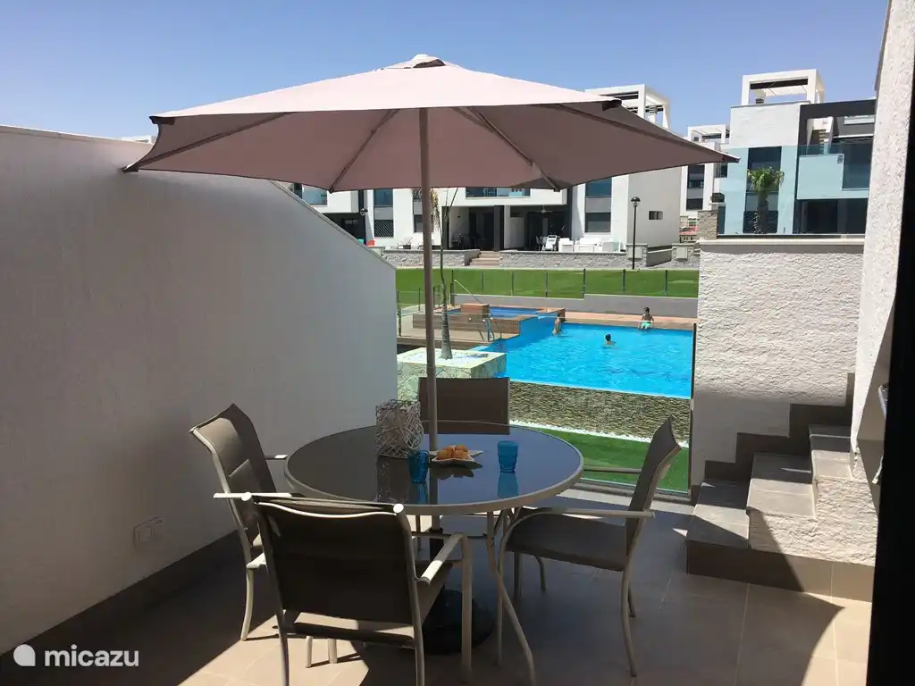 Terrace to the living room with dining table and umbrella.