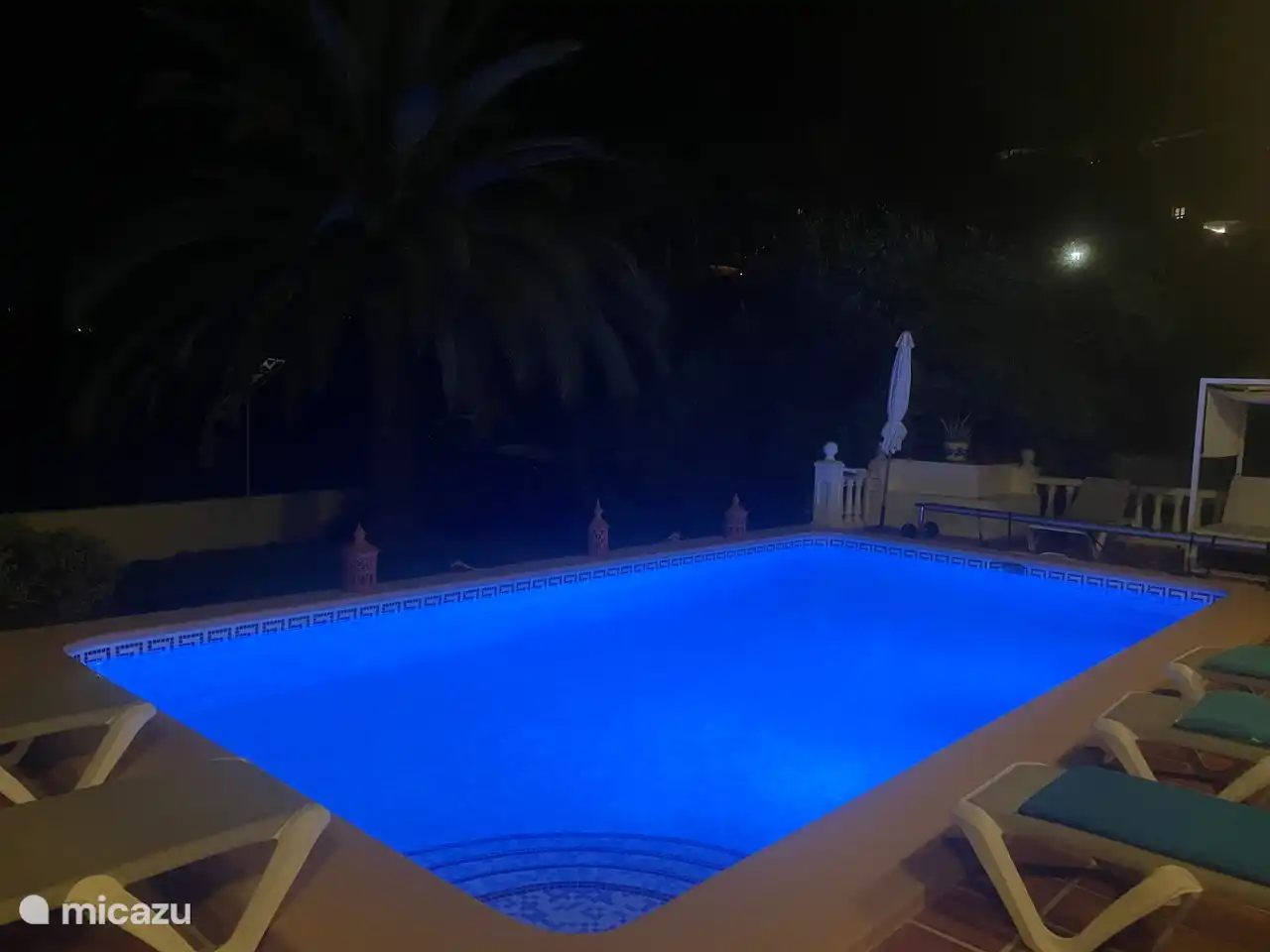 Schwimmbad mit Beleuchtung und genügend Platz mit bequemen Strandliegen