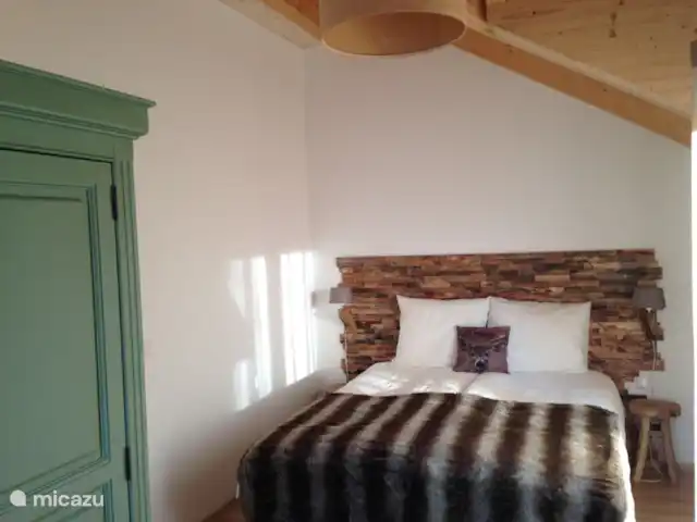 Berghaus Christel en Austria, Carintia, Arnoldstein - casa vacacional Dormitorio 1 (tema de ciervos)
con cama doble con pared trasera y techo con vigas. Esta habitación está orientada al sur y tiene acceso directo al gran balcón.