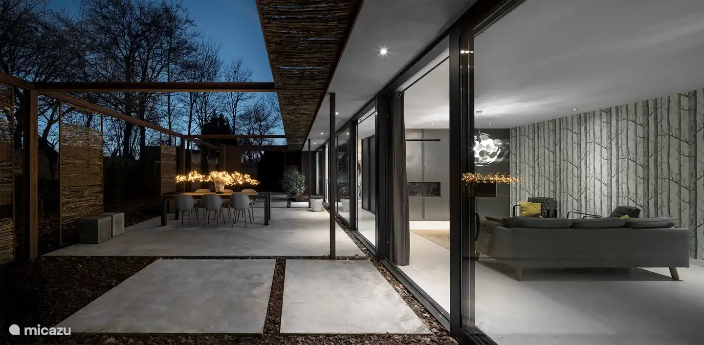 Seite des Hauses mit großen Schiebetüren, die viel Licht spenden. Direkter Zugang zur Terrasse, auf der sich die Sauna und der Whirlpool befinden.