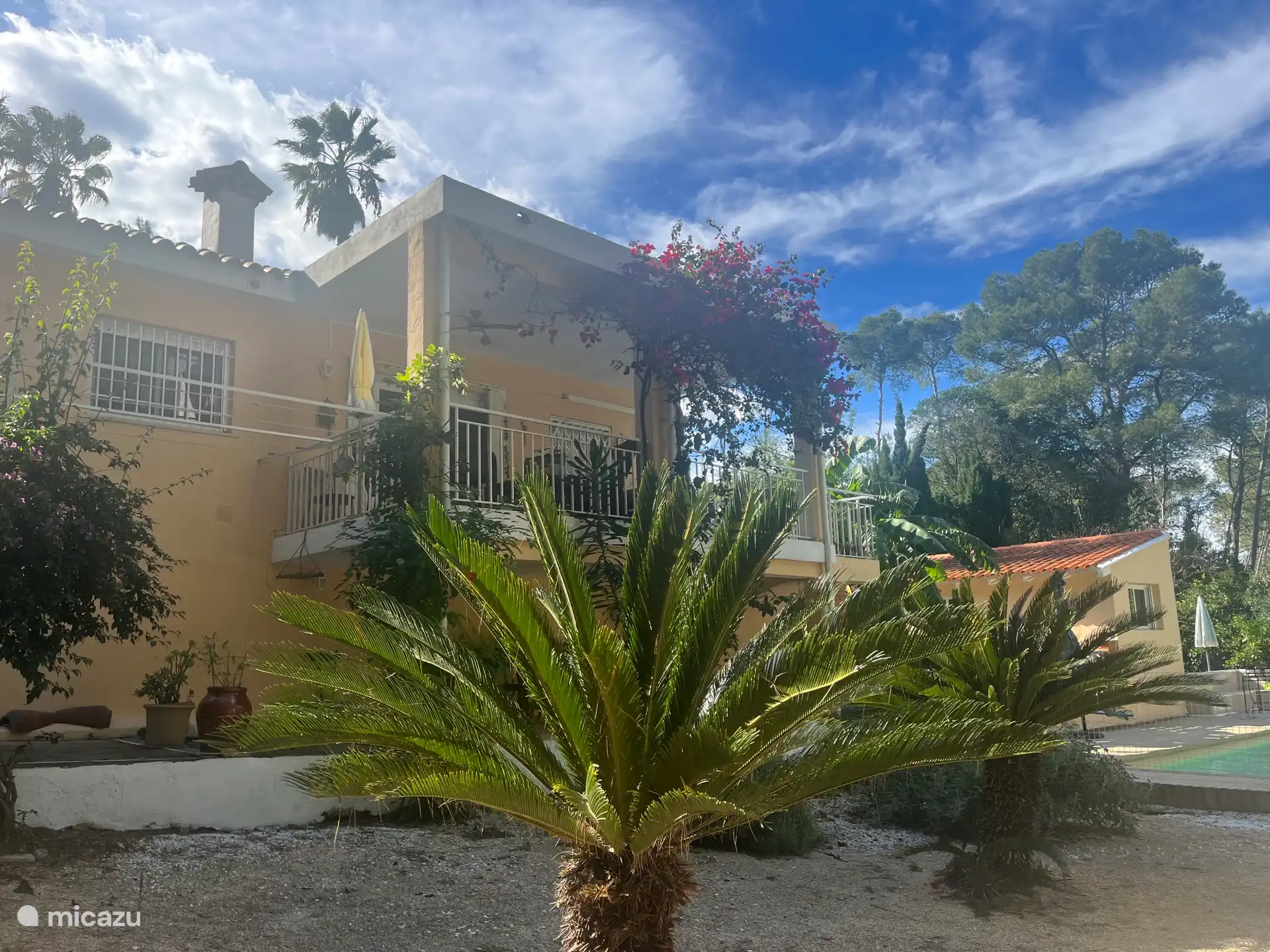 Der Vorgarten vor dem Haus, der Balkon. Im Hintergrund das große private Schwimmbad.