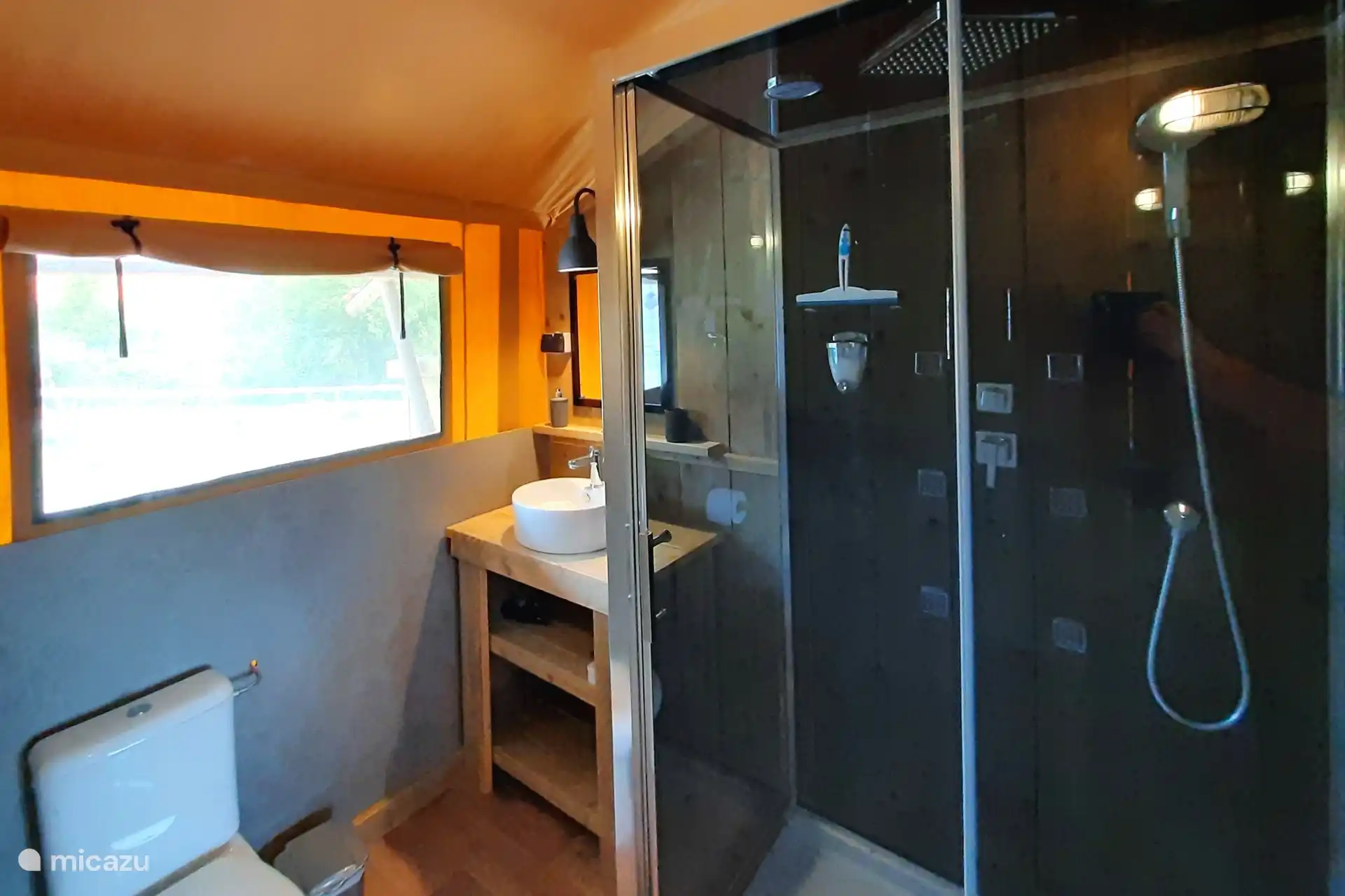 Das Badezimmer mit regen Dusche, Waschbecken und Toilette