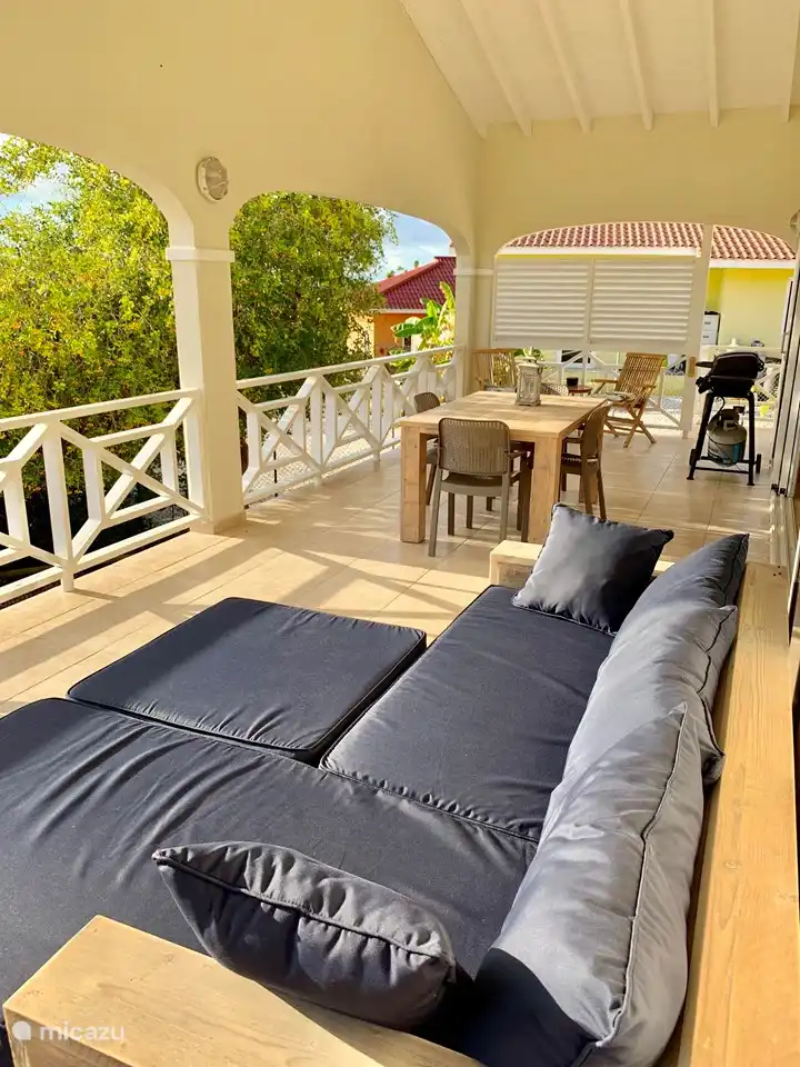 Terrace of the house with dining table, lounge sofa and sitting area. It is connected to the living room and the open kitchen through the sliding door.
