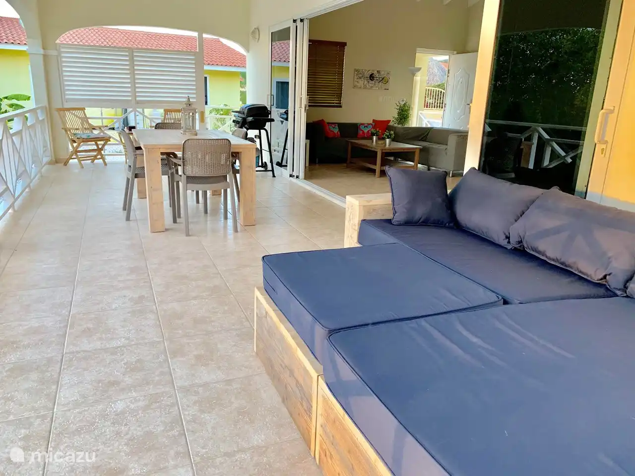 The spacious covered terrace with seating, dining table and lounge sofa, which connects to the living room and open kitchen through a wide sliding door.