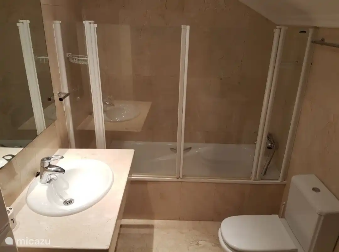 Salle de bain avec baignoire/douche, lavabo et toilettes.