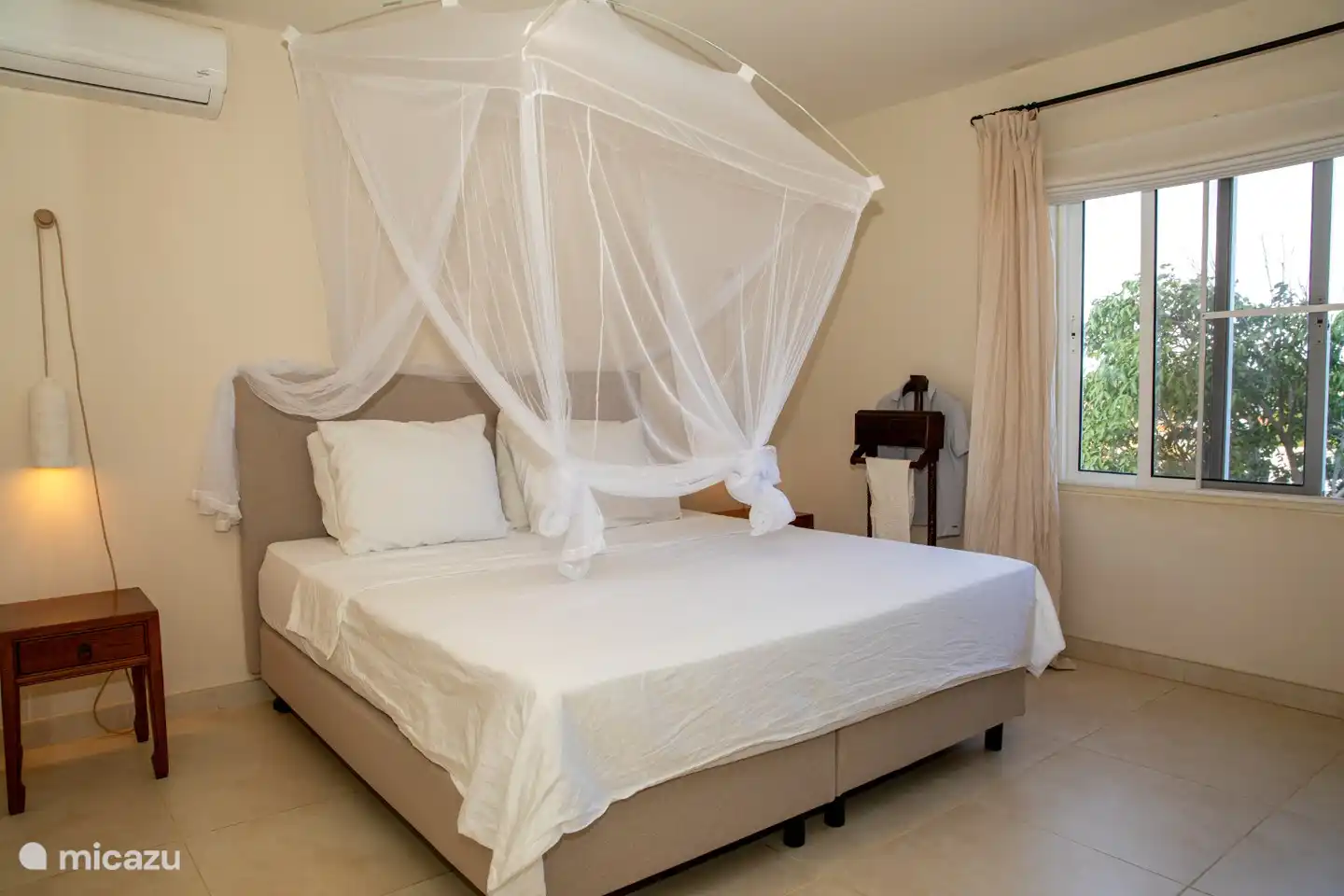 Slaapkamer met heerlijk nieuw bed voorzien van airco en een klamboe.