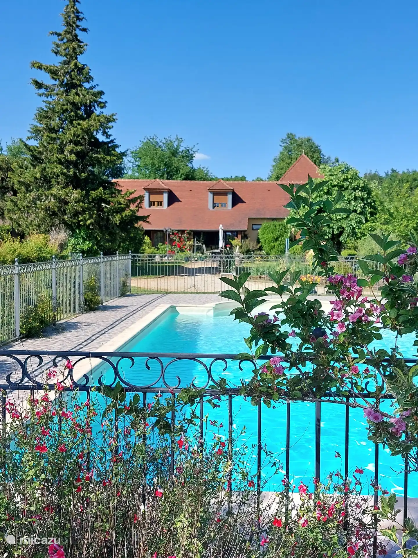 Vue sur la piscine jusqu’à la maison avec à droite, mais légèrement à l’arrière, le gîte. Ainsi, tout le monde a sa terrasse privée.