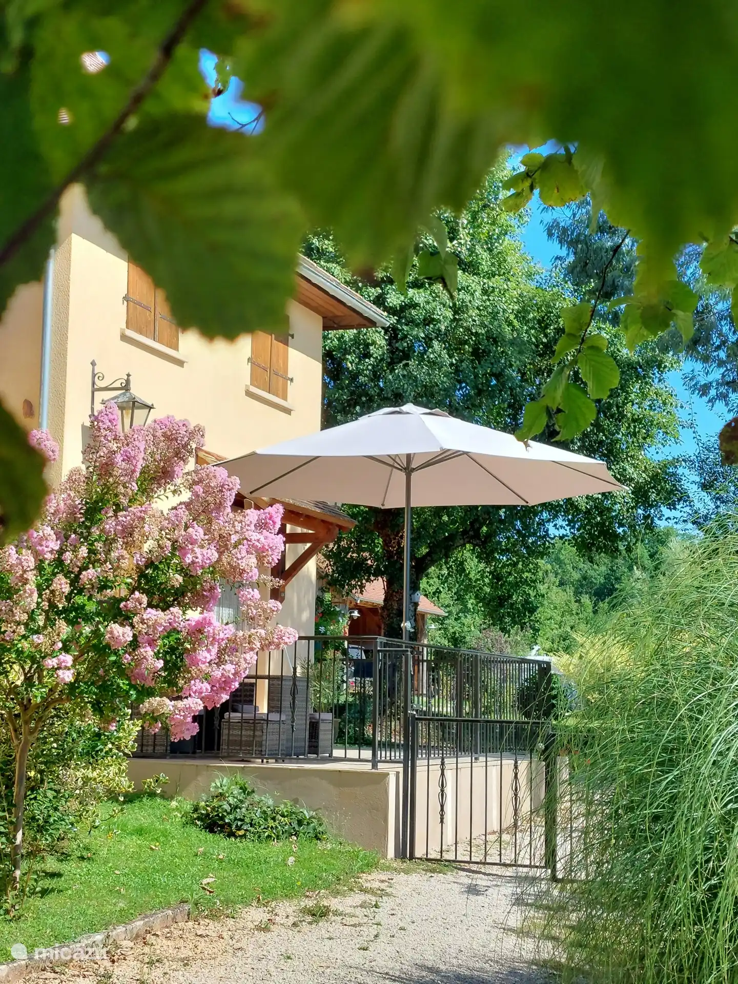 Gîte à l’avant avec terrasse, jardin et vue sur les environs du parc jusqu’à la piscine. 