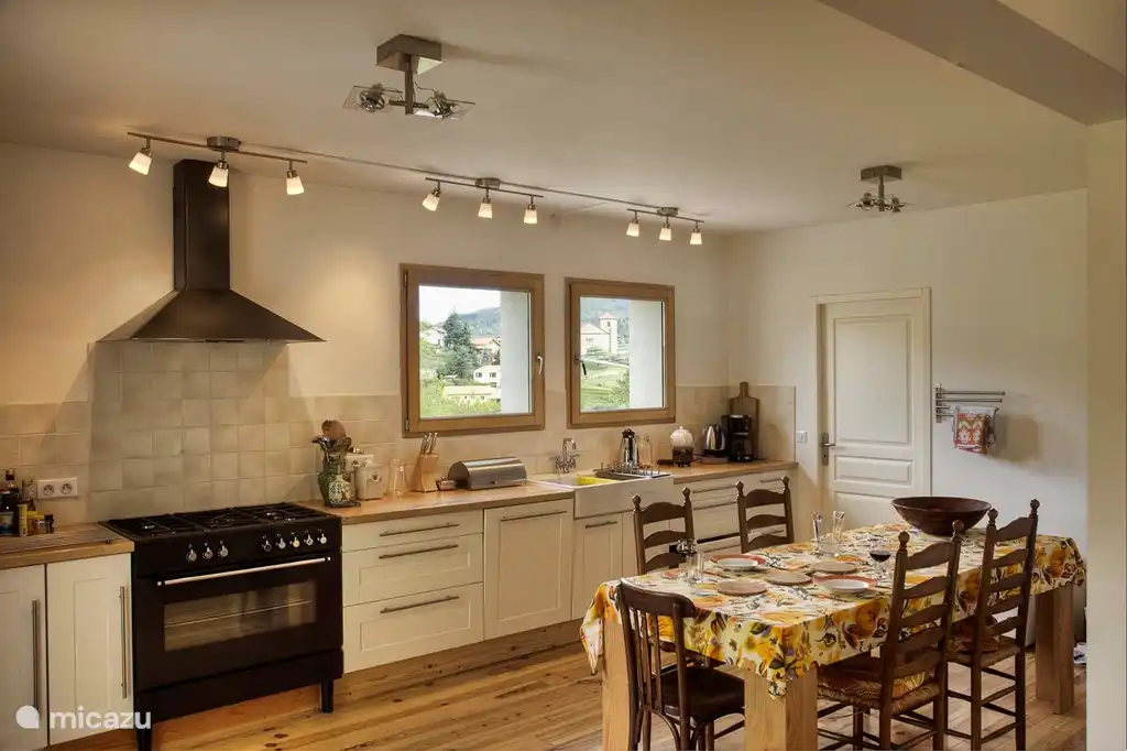 Gut ausgestattete moderne offene Küche mit Essbereich, Geschirrspüler, Kühlschrank, Fünf-Flammen-Herd und großem Backofen. Die Küche ist mit Gewürzen und Öl ausgestattet.