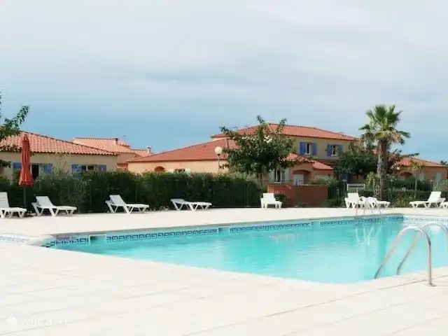 Location de Vacances France, Pyrénées-Orientales, Le Barcarès, villa - Villa 8 La Tulipe Orange La piscine collective dans le parc avec des transats confortables et des palmiers qui se balancent