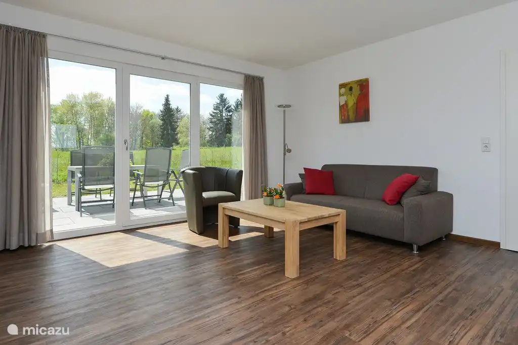 Salon spacieux avec portes-fenêtres donnant sur un jardin privé avec terrasse.