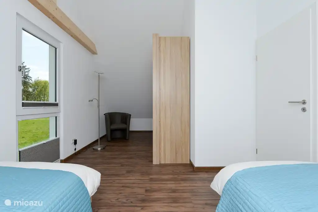 Grande chambre avec deux lits simples au 1er étage avec une grande armoire.