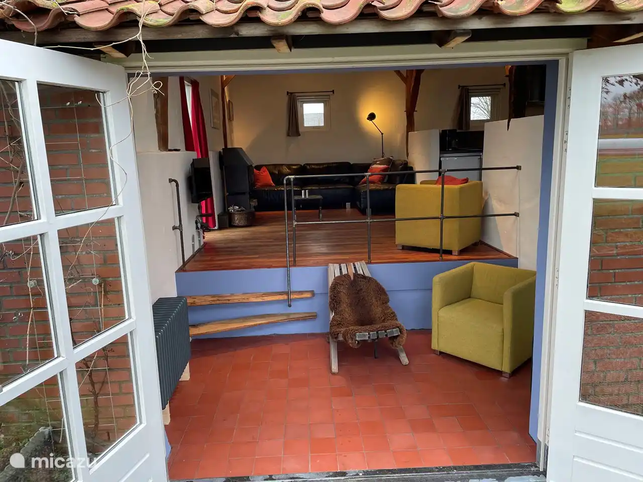 Französische Fenster, Sofa und Holzofen.