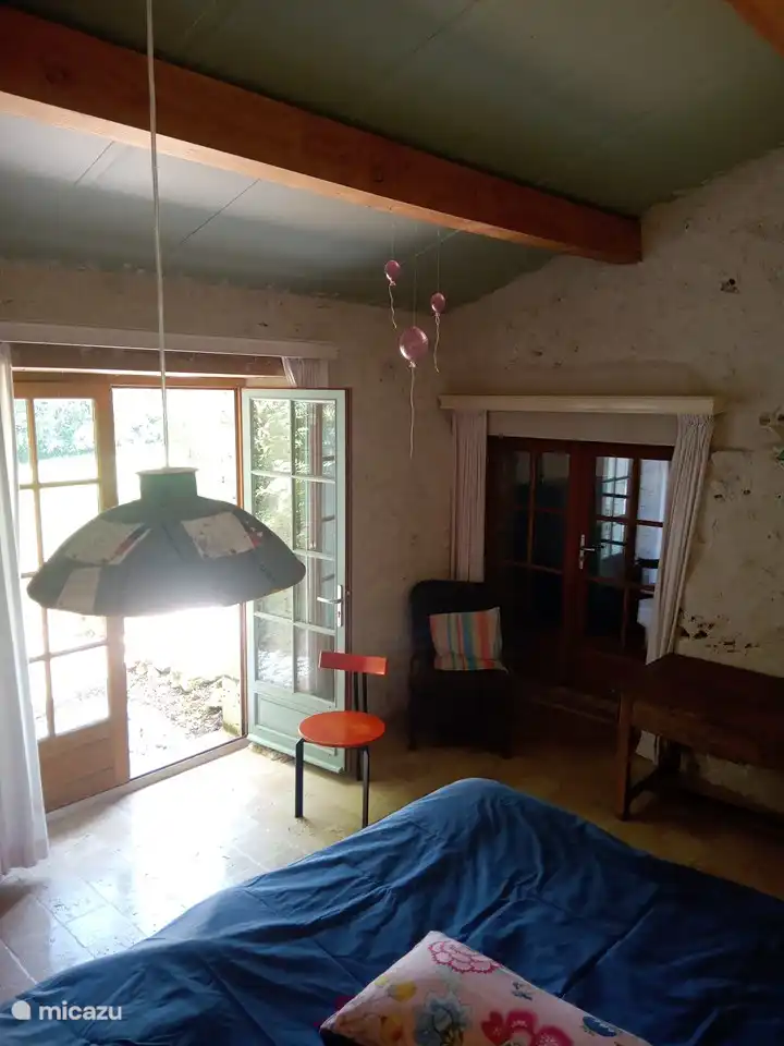 Hauptschlafzimmer mit Doppelbett und Terrassentüren zum Tal hinter dem Haus und zu einem Weg, der auf der Terrasse hinter der Küche endet