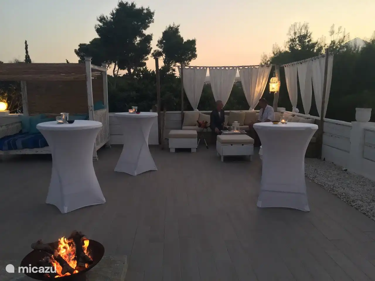 Lounge-Bereich am Pool am Abend mit Stehtischen für Partys