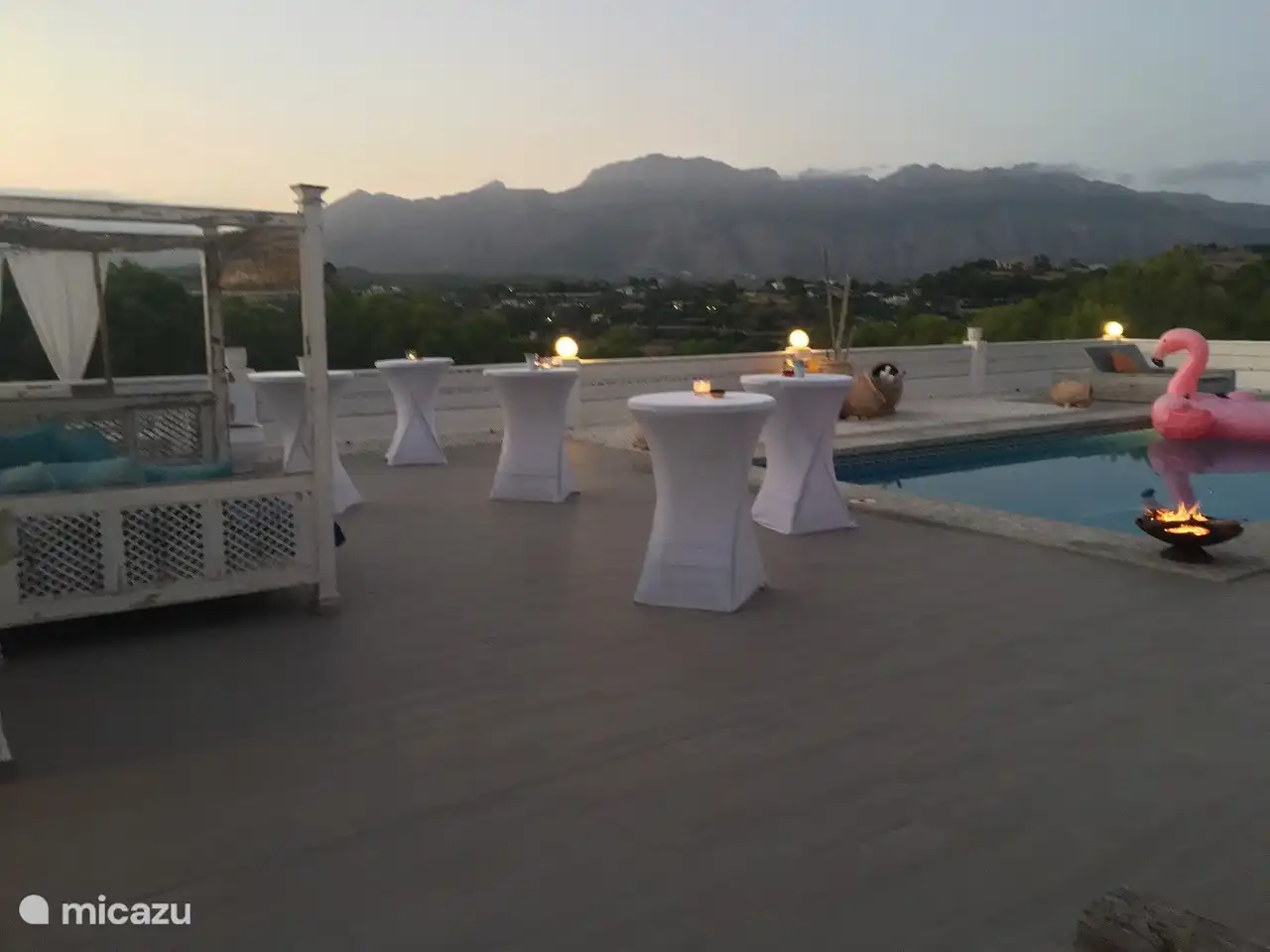 Loungebereich am Pool am Abend mit Stehtischen für Partys und schönen Sonnenliegen für 2 Personen