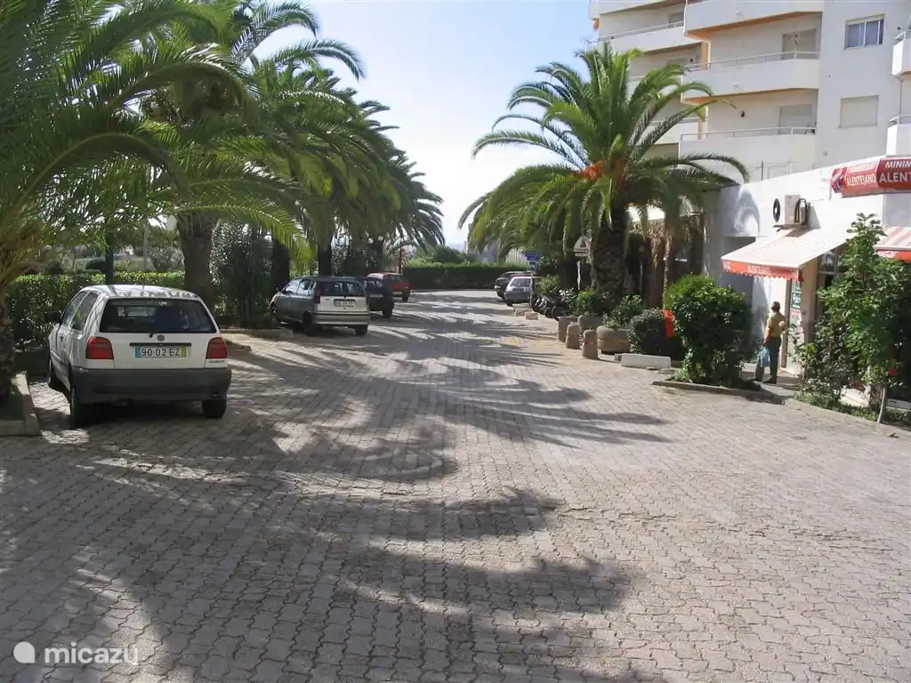 Parkeerplaats voor het gebouw met  supermarkt naast de ingang.