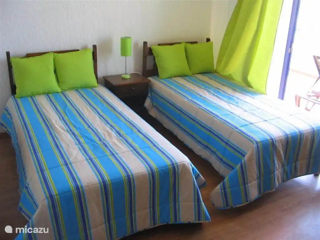 Groene slaapkamer met driedelige wandkast en direct toegang tot het terras.