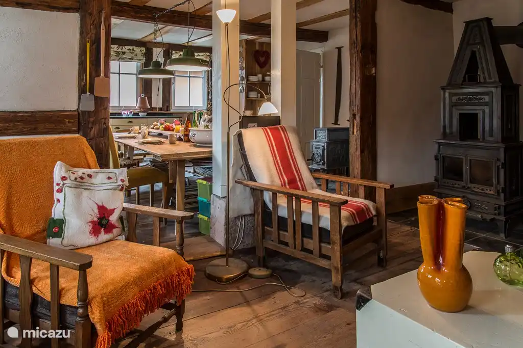 Das gemütliche Wohnzimmer mit großem Holzofen und Blick durch in die Küche. Schöne Stühle und eine Bank. Auf dem Schrank können Kerzen angezündet werden. Und im Schrank die Wanderkarten und Spiele zum Spielen mit Familie oder Freunden.