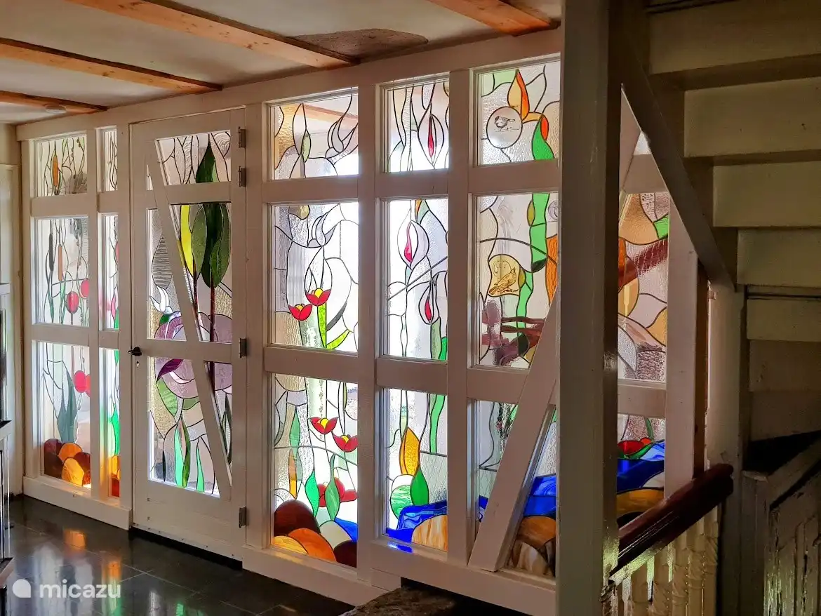 Die große Halle am Eingang ist in 2 Teile unterteilt. Genau in der gleichen Ausführung wie die Fachwerkwand an der Außenseite gibt es eine extra Wand mit selbstgemachtem Buntglas. Die Kälte des Winters wird aus dem Wohnbereich ferngehalten und bietet viel Komfort.