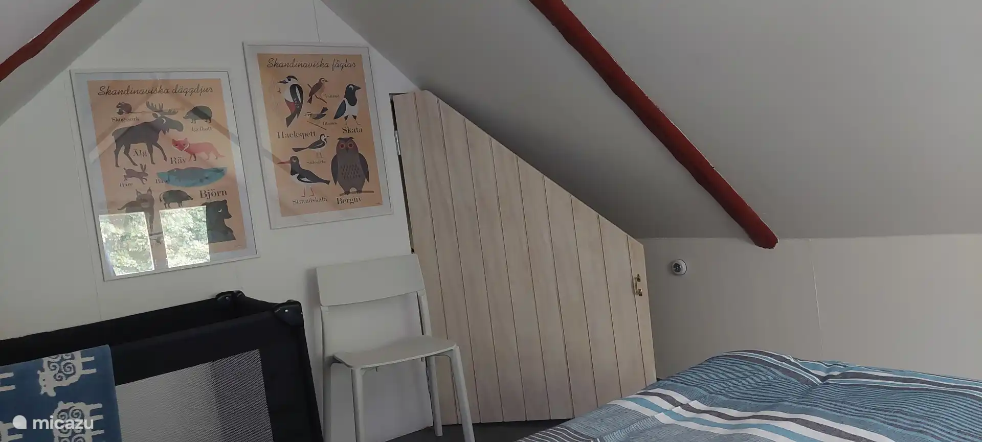 Slaapkamer boven met verduisterende gordijnen en kampeerbedje.