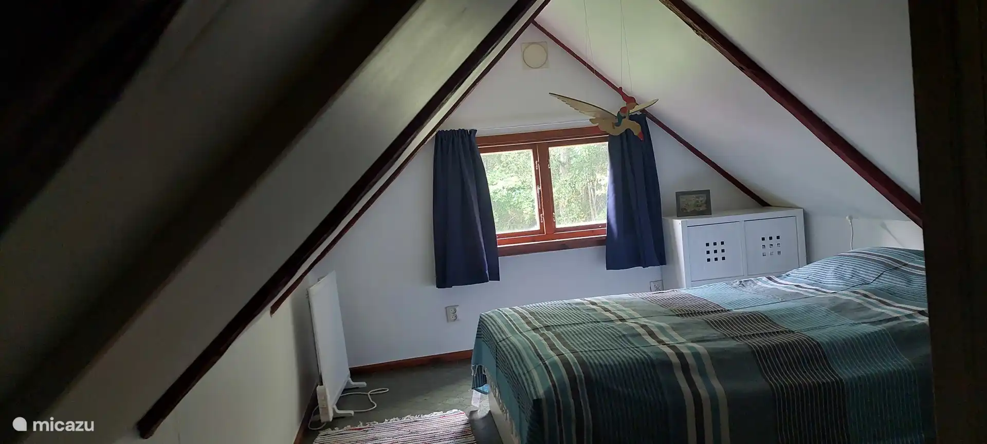 Rechter slaapkamer boven met verduisterende gordijnen. Er moet even gebukt worden om door de deur te kunnen. Minder goed toegankelijk voor lange mensen