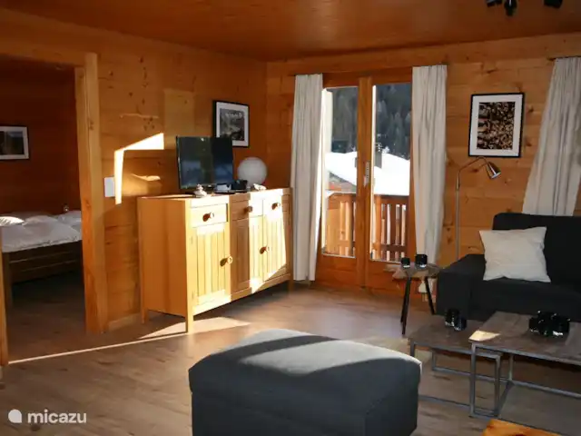 chalet huren in Zwitserland, Wallis, Fiesch – Chalet Valais Woonkamer met TV en openslaande deuren naar balkon, met prachtig uitzicht op het dorp Fiesch en Ernen.
WII aanwezig.