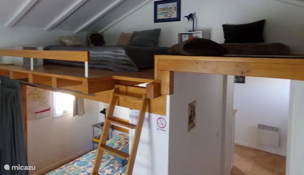 Wohnzimmer mit 2 Betten, Esstisch und offene Küche. Auf Mezzanine kleinen 2-Bett