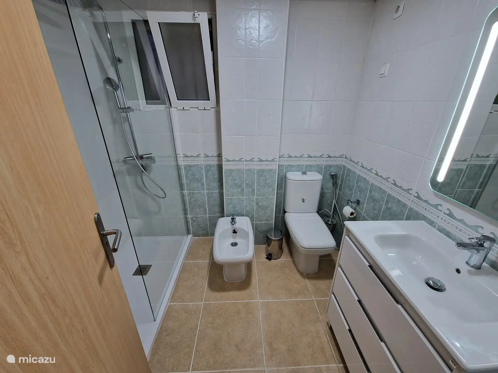 Badezimmer 1 mit ebenerdiger Dusche, Bidet, Toilette und Waschbecken.