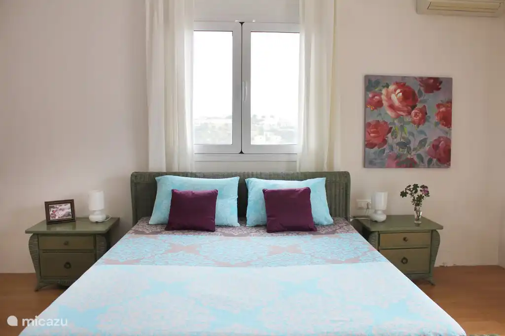 Chambre avec un lit double et balcon.