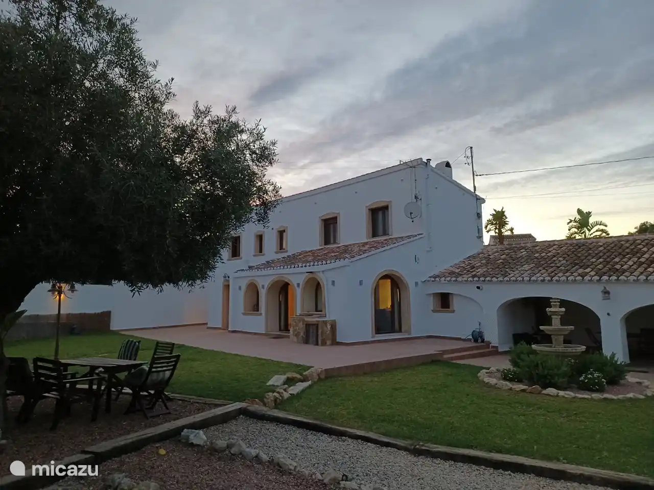 avondzicht op woning, met terras onder de olijfboom