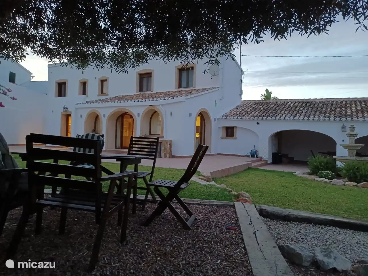 zicht vanaf terras onder de olijfboom op de woning