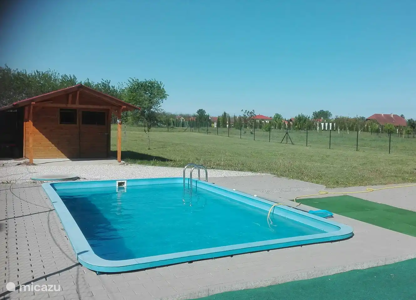 Piscina en el patio trasero con cenador con terraza sombreada con vistas a la piscina.