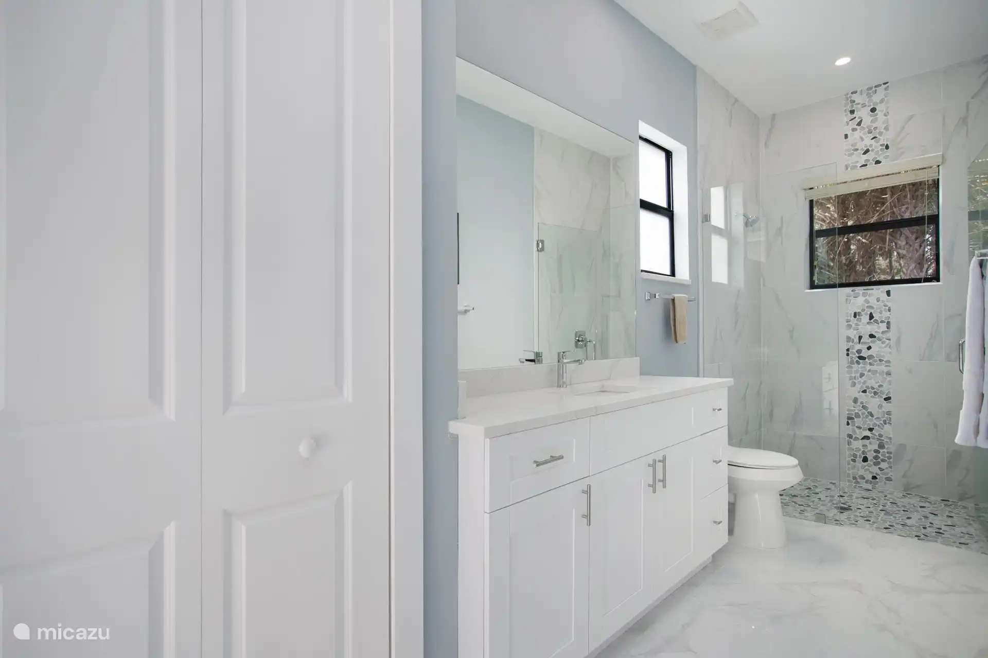 zweites Badezimmer mit ebenerdiger Dusche, Schränken, Waschbecken und Toilette mit Hand-Bidetbrause