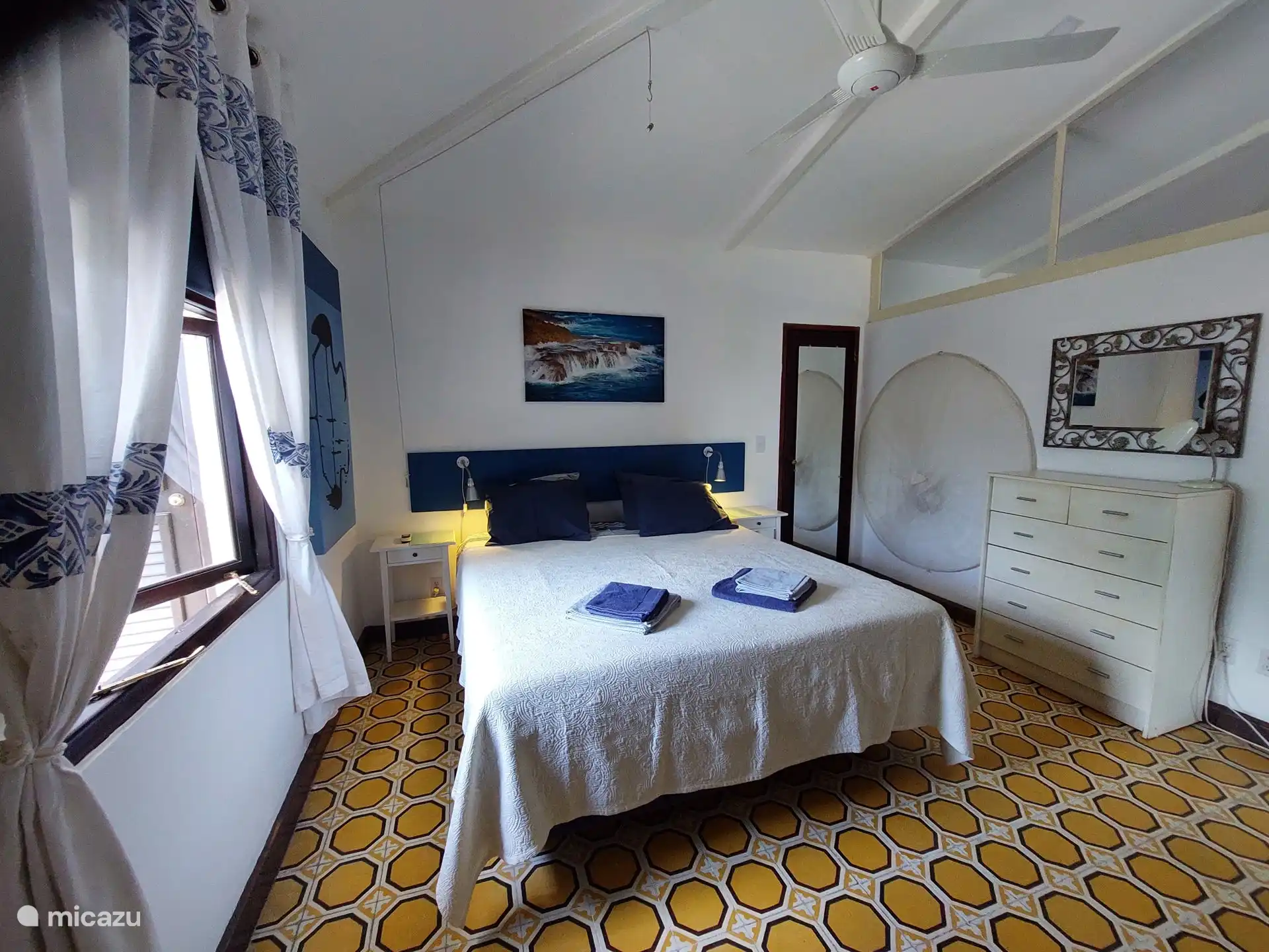 Aan de muur rechts hangt een twee persoons klamboe.