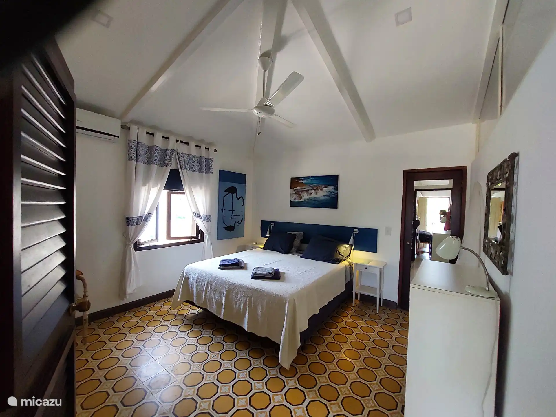 De master bedroom, is naast een ruim comfortabel tweepersoons bed, voorzien van airconditioning en een plafondventilator.  Achter de deur links bevindt zich een grote kastenwand. 