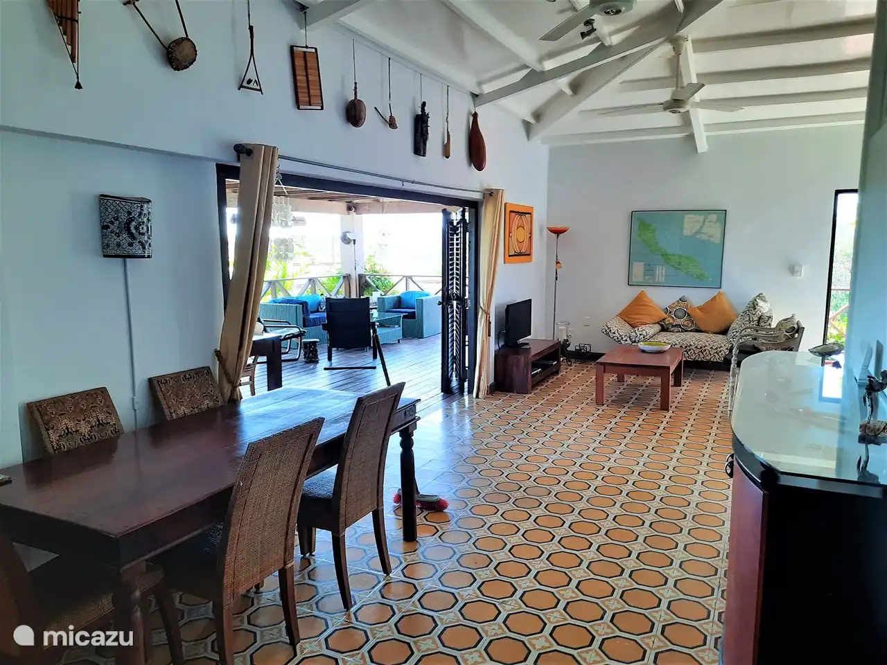 In de woonkamer hangen twee grote plafondventilators die de ruimte koel houden. Hier is het met de computer fijn werken aan de grote tafel