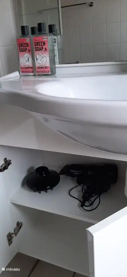 Dusche mit einem Fön im Schrank. Zusätzlich zu Marcel's veganem Shampoo und Duschgel.