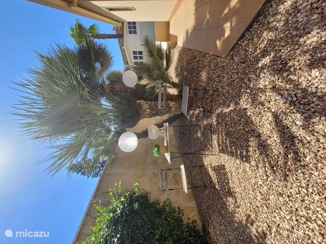 Ambiente ajardinado lado de la casa. Con una casita de jardín al fondo.