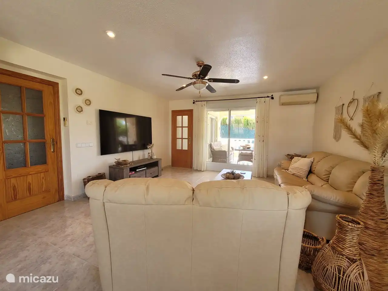 Amplia sala de estar con calefacción por suelo radiante, aire acondicionado, ventilador, cómodo sofá y TV grande