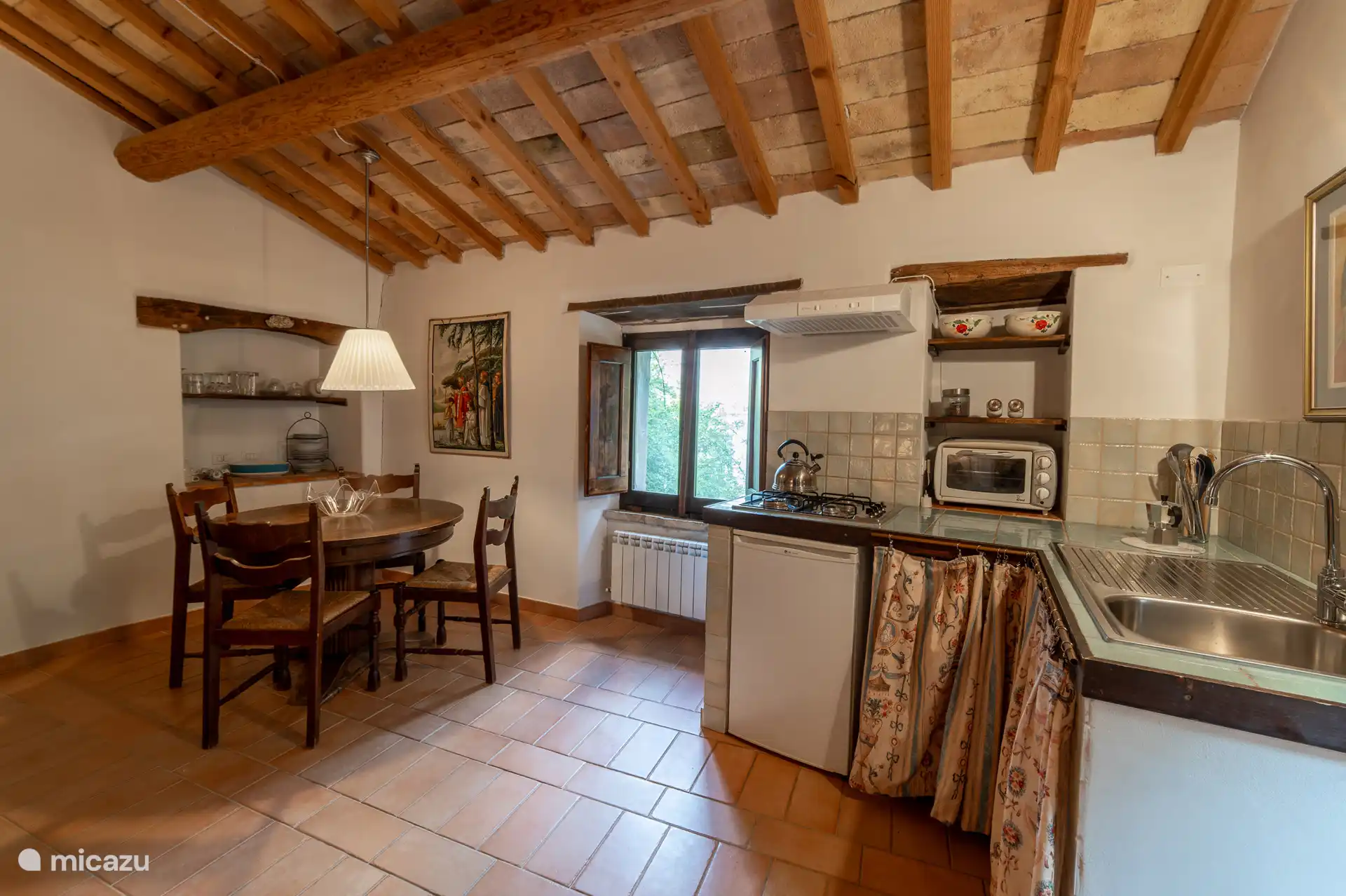 Volledig uitgeruste kitchenette met kookplaat, klein oventje en een eettafel voor vier personen. 