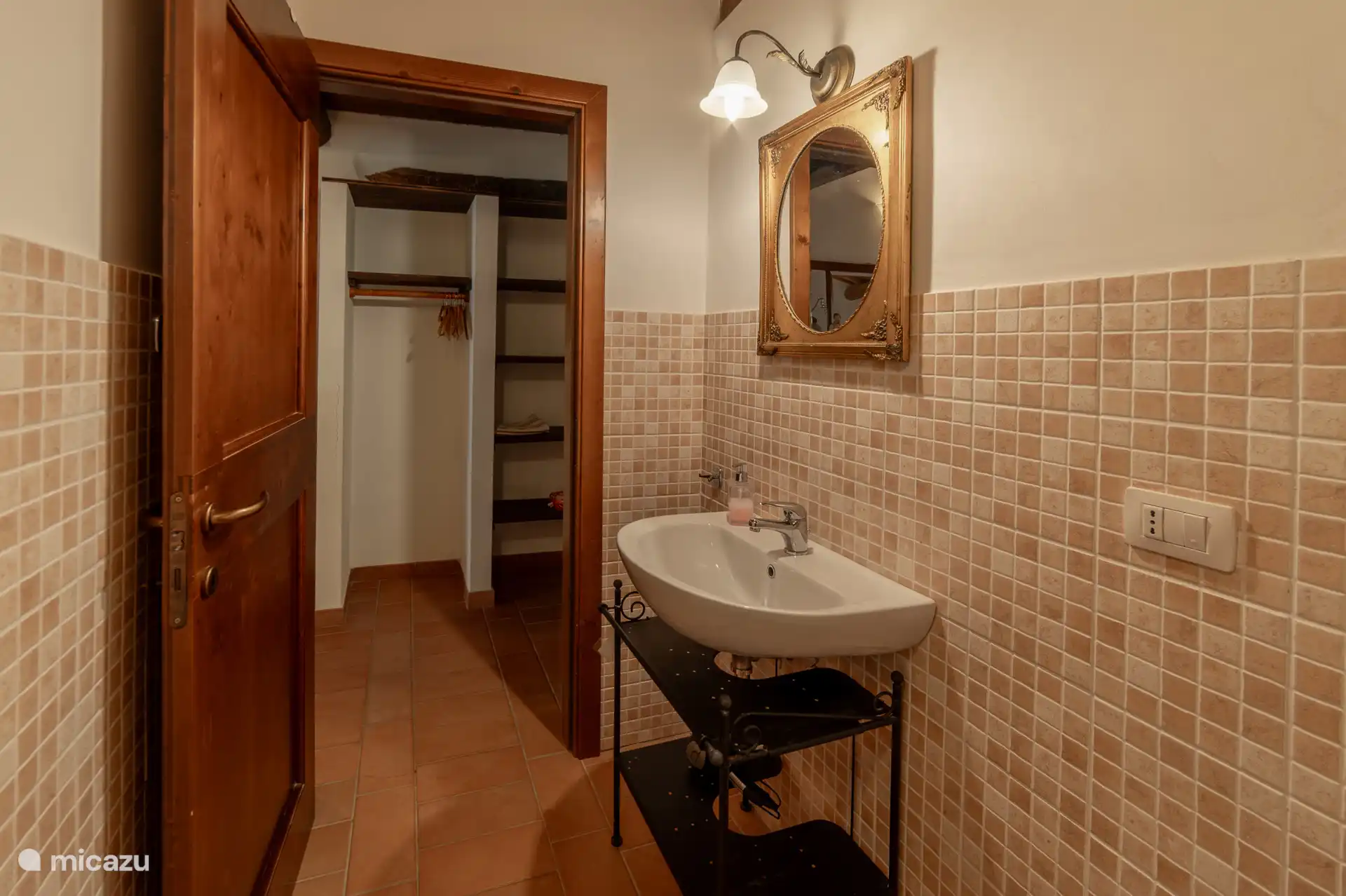 Badkamer met wastafel en in de hal een open kledingkast.