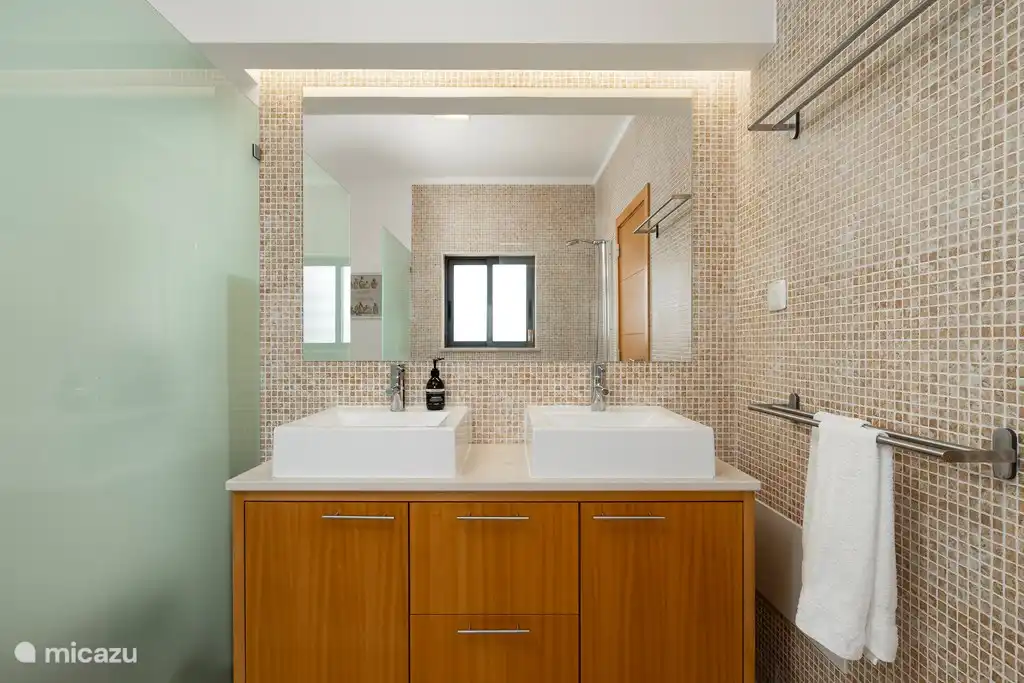 Badezimmer im Schlafzimmer mit Doppelbett.