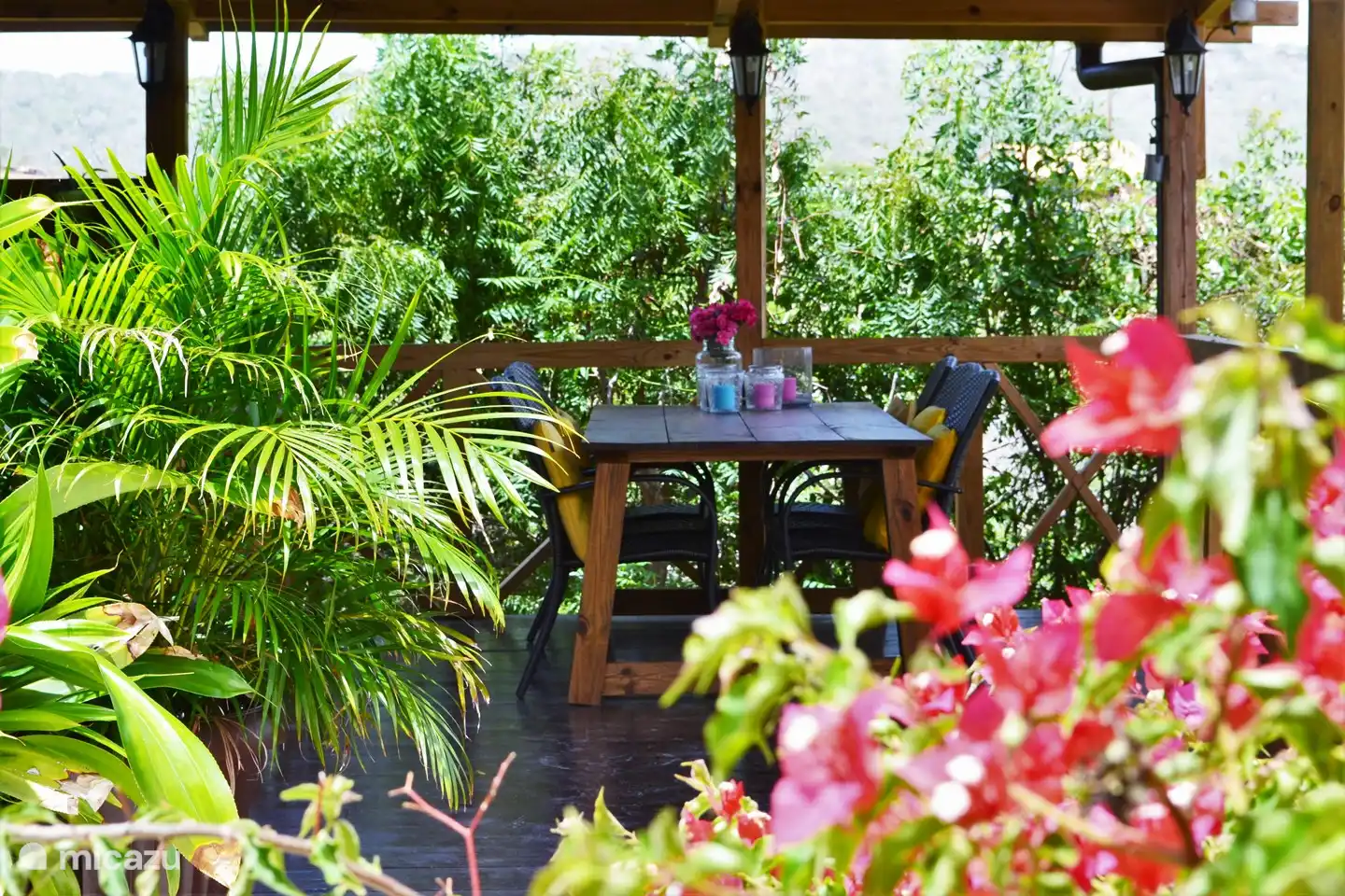La cocina exterior, cerca del estudio, con mesa de comedor a la sombra y una pequeña biblioteca.
