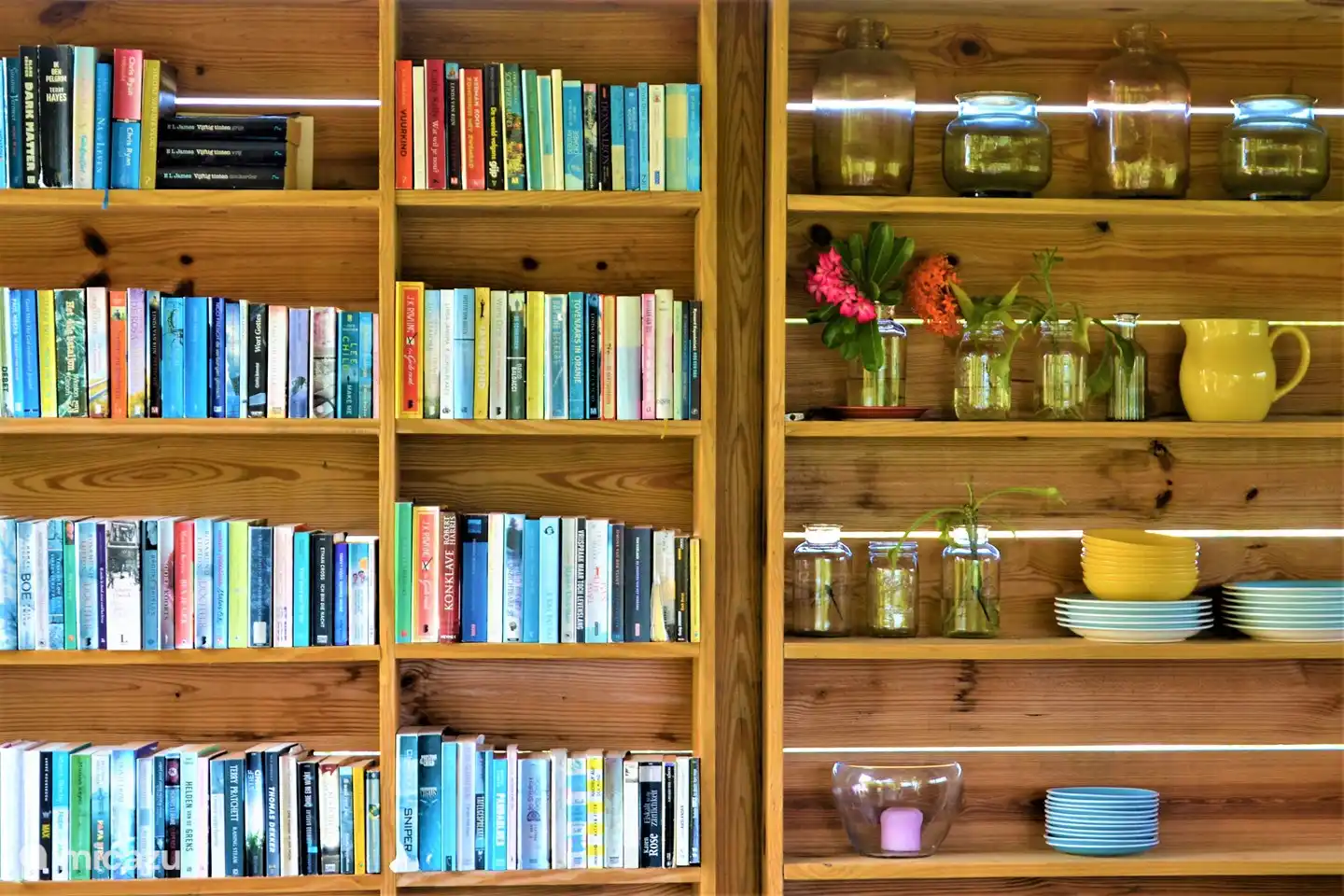 La cocina exterior, cerca del estudio, con mesa de comedor a la sombra y una pequeña biblioteca.