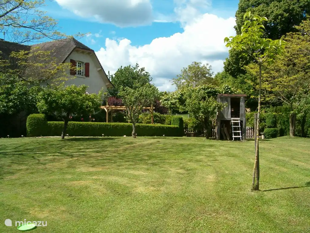 Teil des privaten Gartens mit Baumhaus und Esstisch im Freien