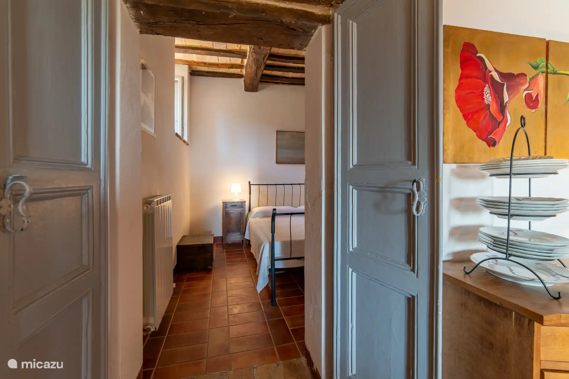 Een doorkijkje door de originele blauwe deuren. De charmante ingang naar de slaapkamer van Melograno, vol authentiek Italiaans karakter. 